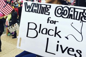 person holding a sign that says white coats for black lives